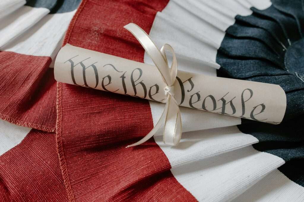 Close-up of a 'We the People' scroll on an American flag cloth background.